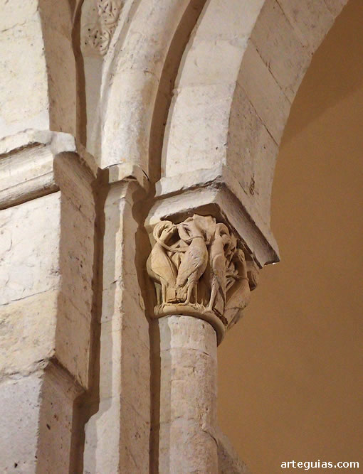 Interior de la cabecera románica con un capitel de aves